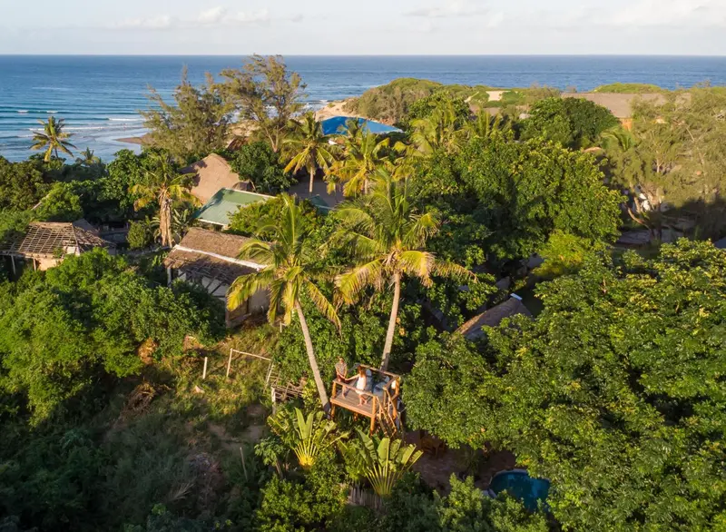 Vue aérienne d'un complexe hôtelier tropical avec végétation luxuriante et piscine.