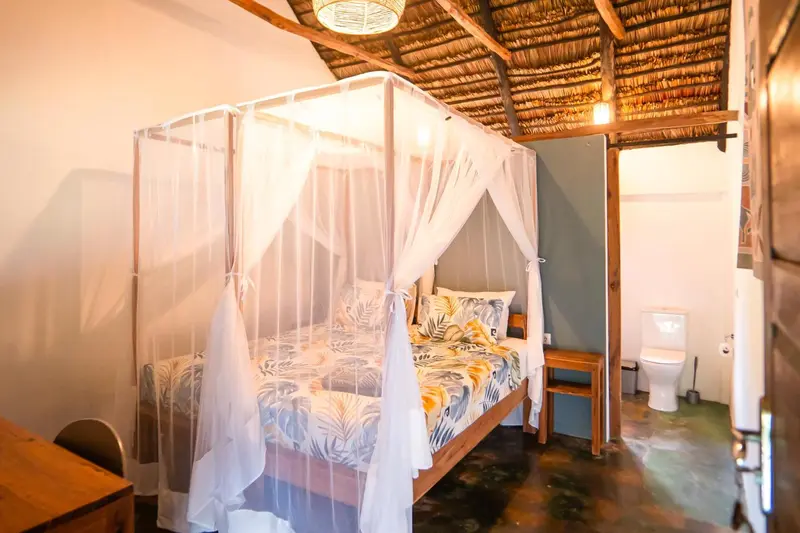Une chambre lumineuse avec un lit à baldaquin et une salle de bain attenante.