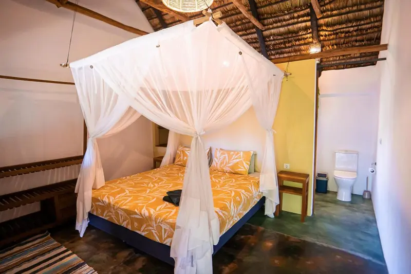 Une chambre lumineuse avec un lit à baldaquin et une salle de bain attenante.