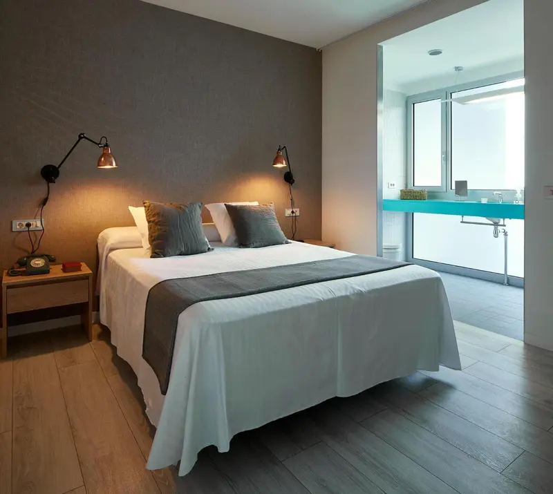 Une chambre lumineuse avec un grand lit et une baie vitrée.