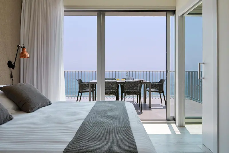 Une chambre lumineuse s'ouvre sur une terrasse avec vue sur la mer.