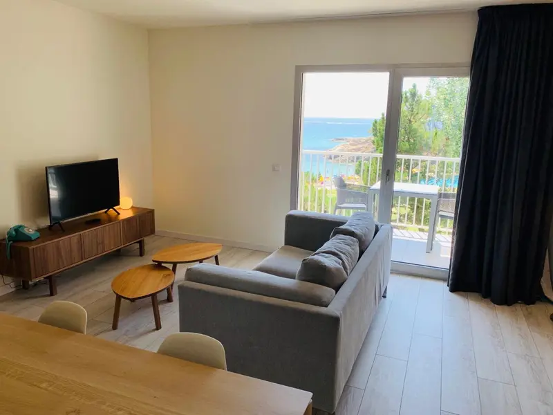 Un salon lumineux s'ouvre sur une terrasse avec vue sur la mer.