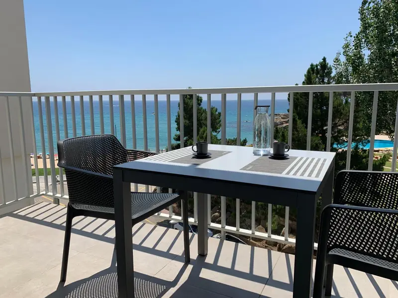 Une table avec des tasses sur une terrasse ensoleillée avec vue sur la mer.