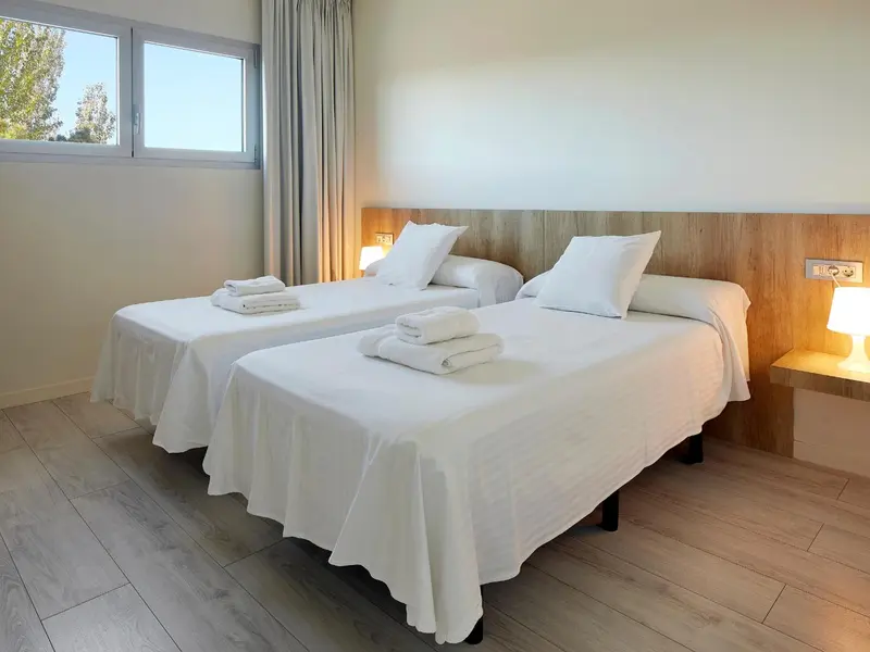 Une chambre lumineuse avec deux lits simples et une décoration sobre.
