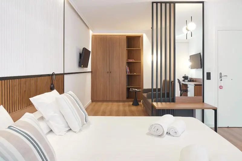 Une chambre lumineuse avec un lit fait et un espace détente.