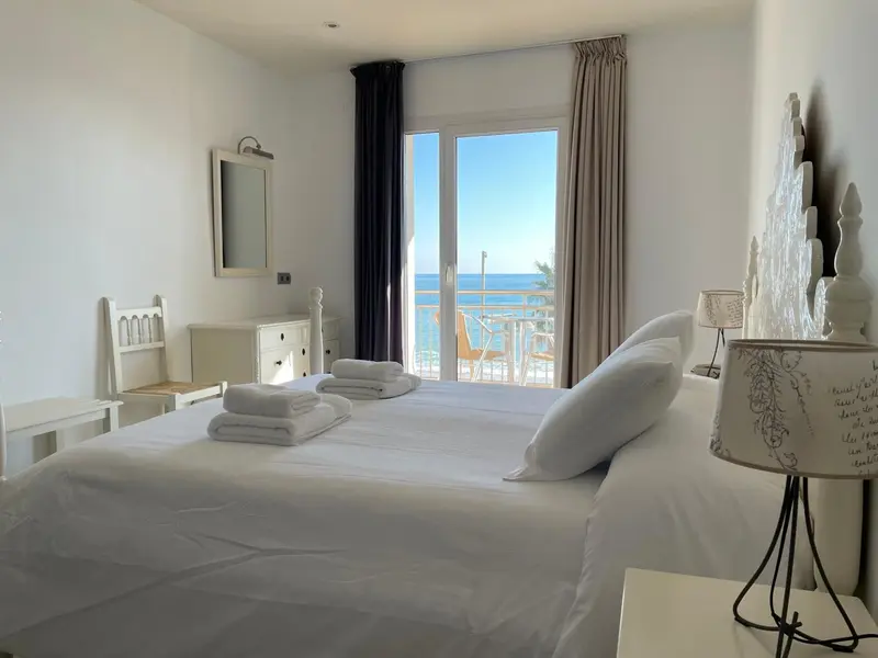 Une chambre lumineuse avec un grand lit donnant sur la mer.