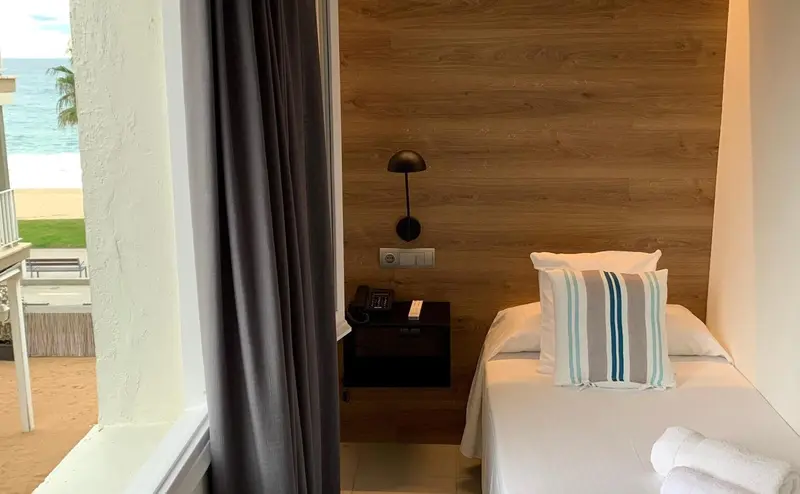Une chambre lumineuse avec un lit simple et une vue sur la mer.