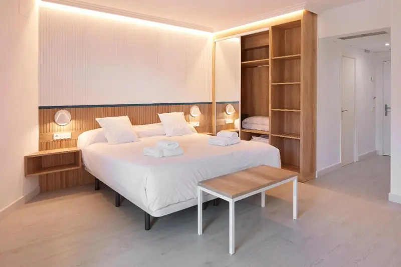 Une chambre lumineuse avec un grand lit recouvert de linge blanc.