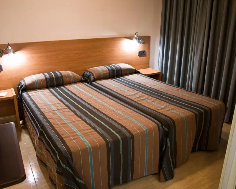 Une chambre avec un grand lit recouvert d'une courtepointe rayée.
