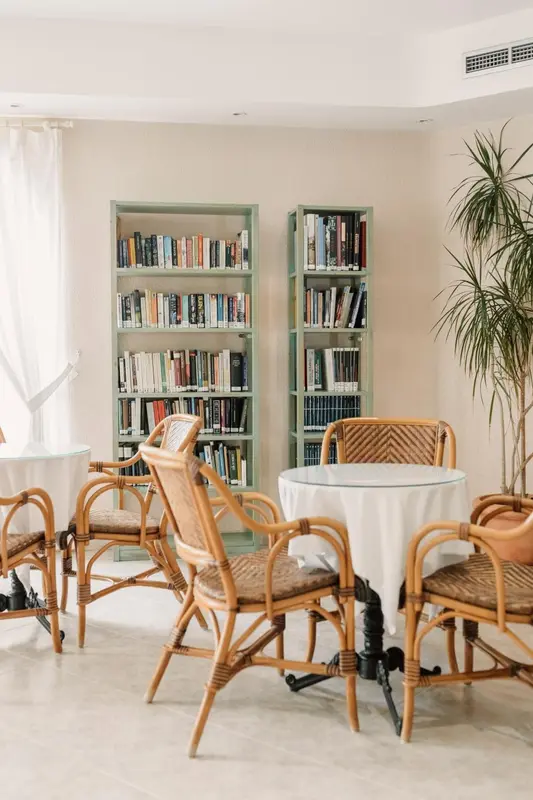 Une bibliothèque lumineuse avec des tables et des chaises en rotin.