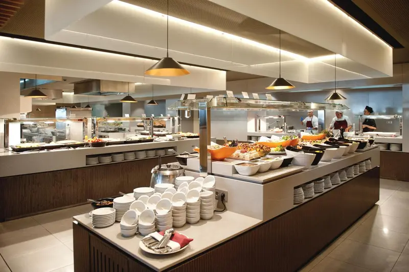 Un buffet propose une grande variété de plats et de salades dans une salle lumineuse.