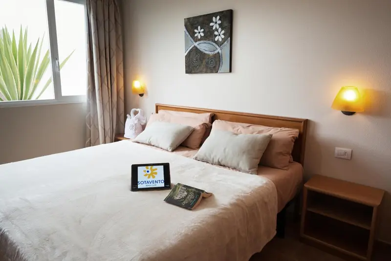 Une chambre lumineuse avec un grand lit recouvert de coussins.