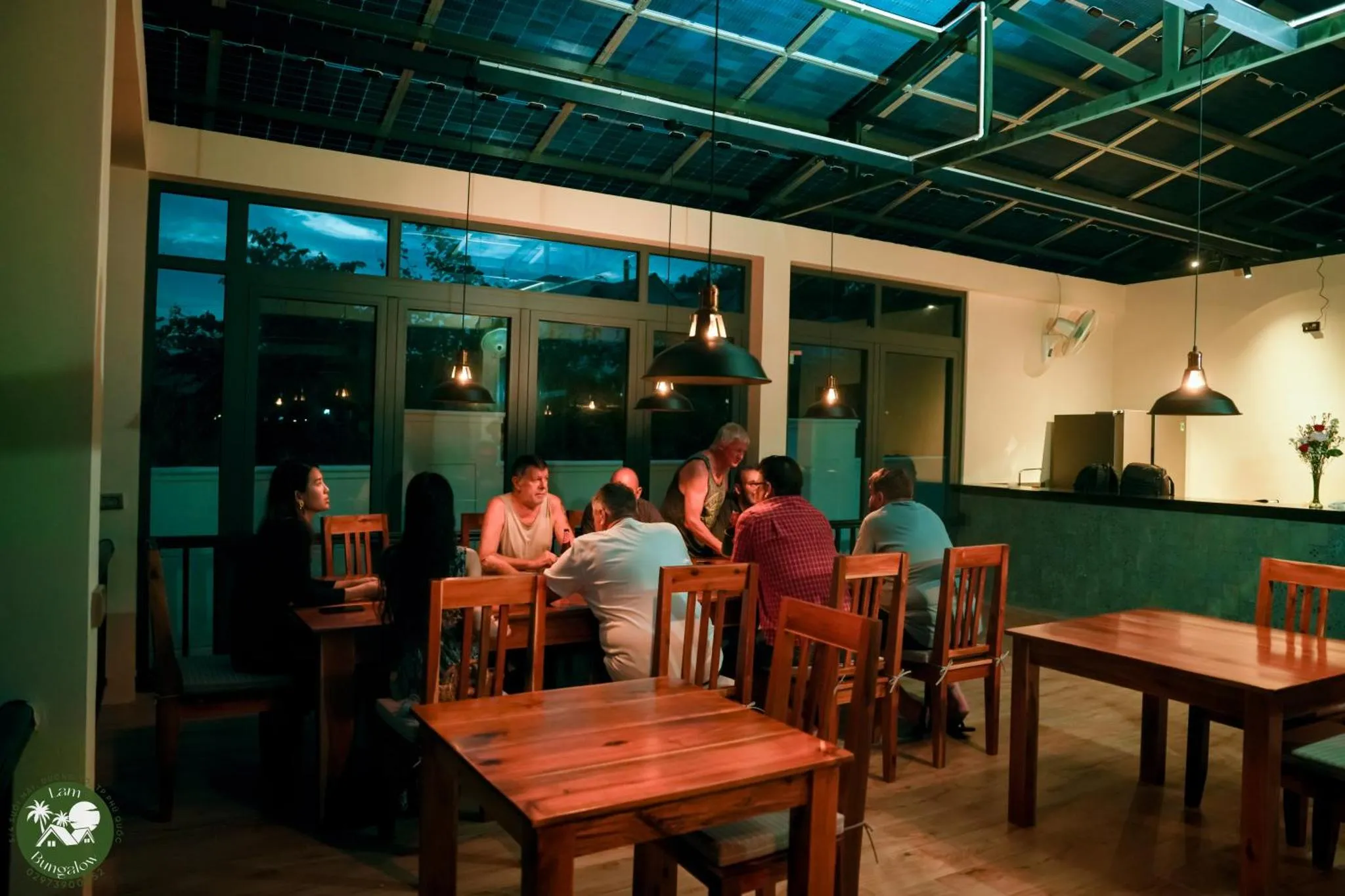 Une salle à manger lumineuse avec des tables en bois et des convives.