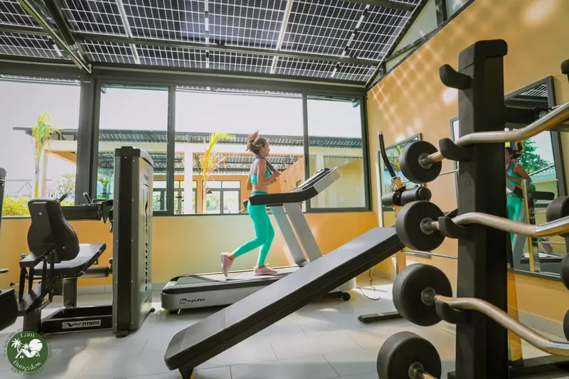 Une femme court sur un tapis de course dans une salle de sport lumineuse.