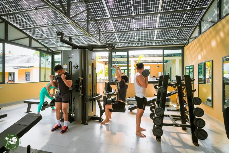 Une salle de sport lumineuse avec des équipements de musculation et des personnes s'entraînant.