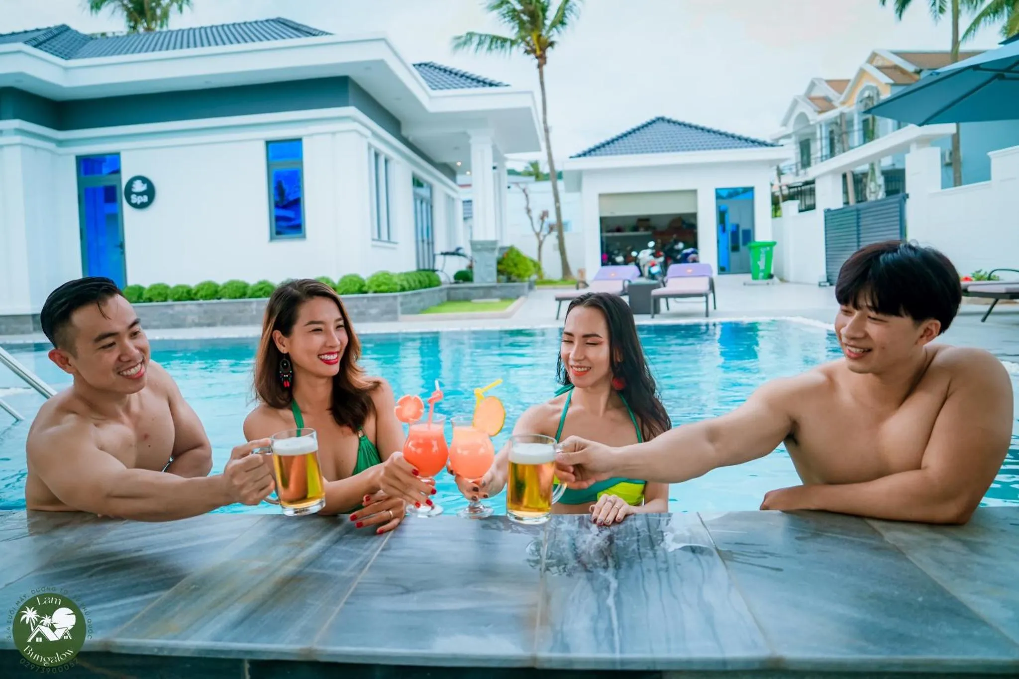 Des personnes sourient et trinquent avec des verres colorés dans une piscine ensoleillée.