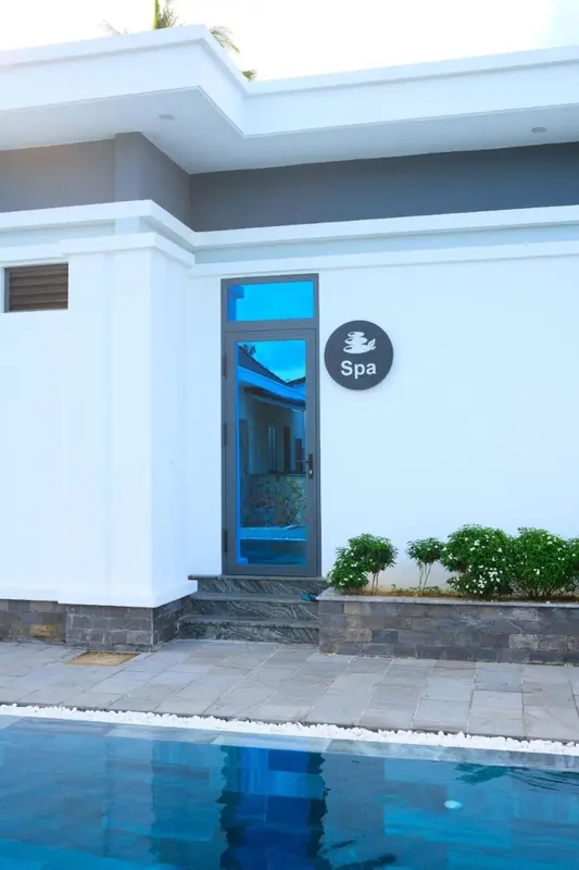 Façade blanche d'un bâtiment avec une entrée bleue et un panneau rond noir.