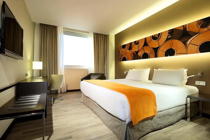 Une chambre d'hôtel moderne avec un grand lit et un bureau.