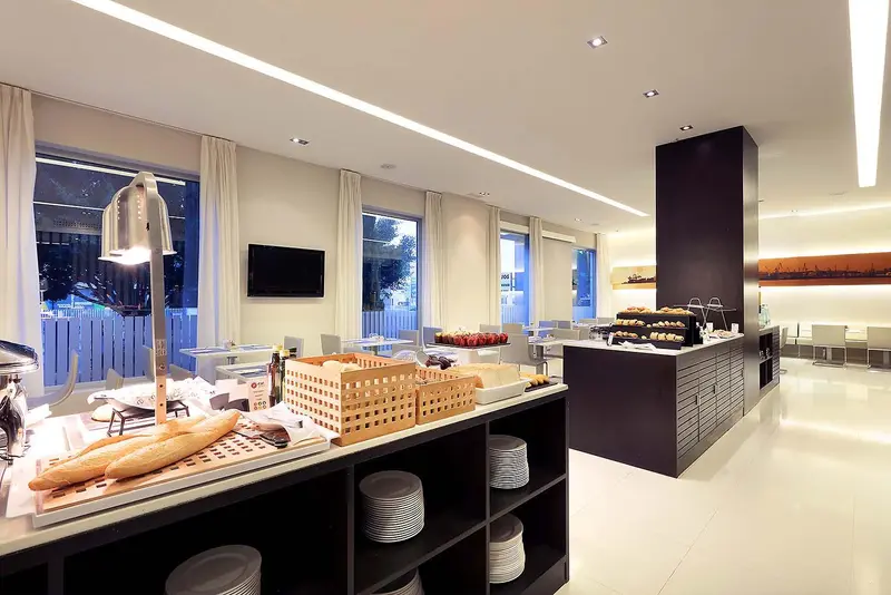 Un buffet propose des viennoiseries et des fruits dans une salle lumineuse.