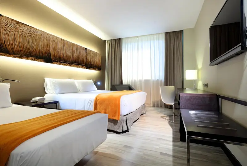 Une chambre moderne avec un grand lit et une fenêtre drapée.