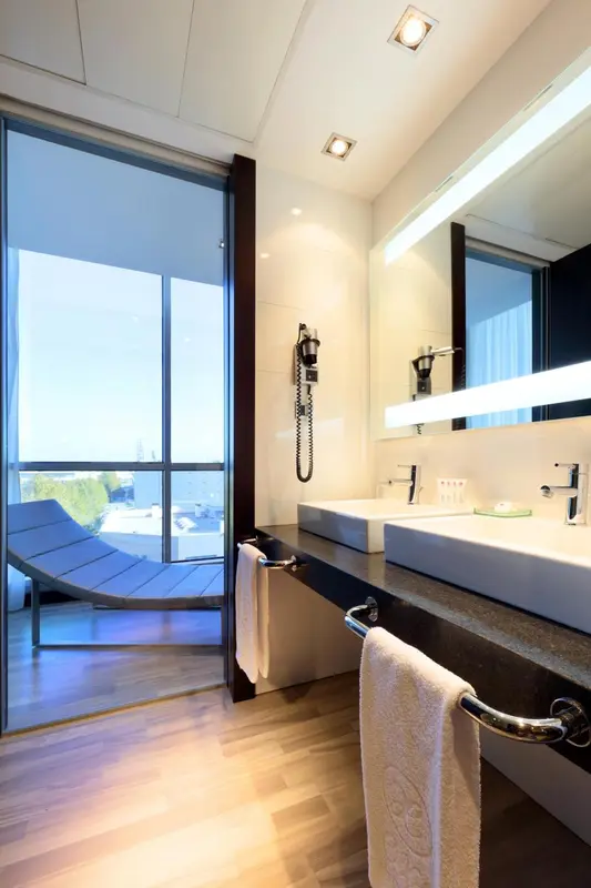 Une salle de bain moderne avec un grand miroir et une vue sur une terrasse.