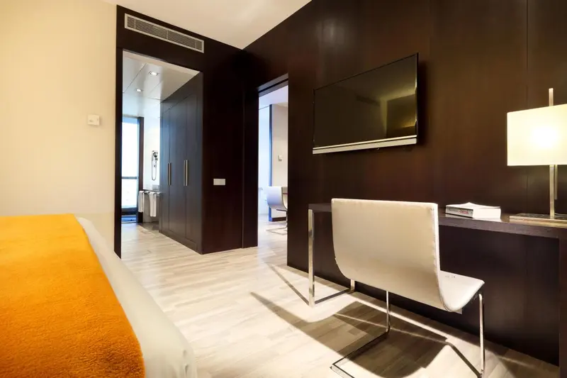 Une chambre moderne avec un lit orange et un bureau blanc.