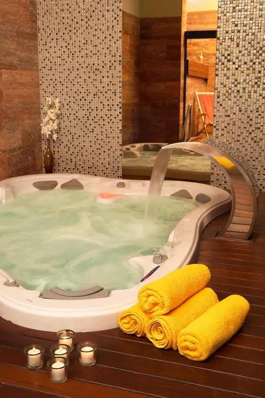 Un jacuzzi intégré dans une salle de bain moderne avec des serviettes colorées.
