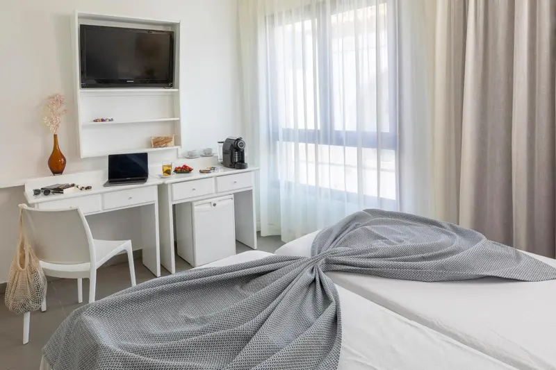 Une chambre lumineuse avec un bureau et un lit préparé.