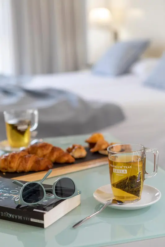 Une table basse en verre présente un petit déjeuner avec des viennoiseries et une boisson.