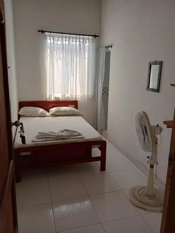 Une chambre simple avec un lit et un ventilateur.