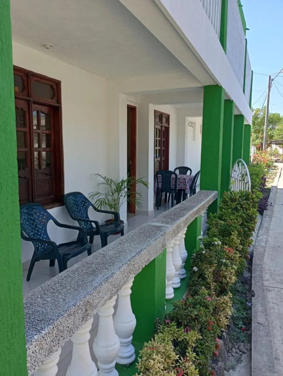 Terrasse ombragée avec mobilier en plastique et plantes vertes.