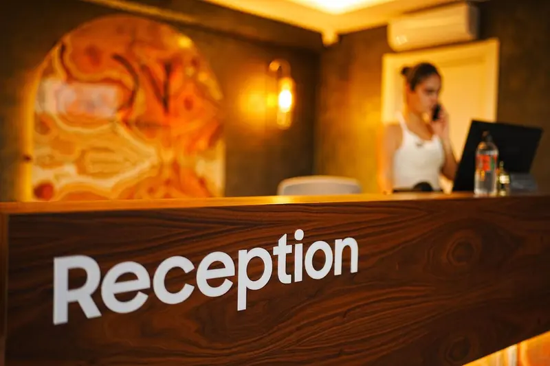 Une réception d'hôtel avec un comptoir en bois et une employée au téléphone.