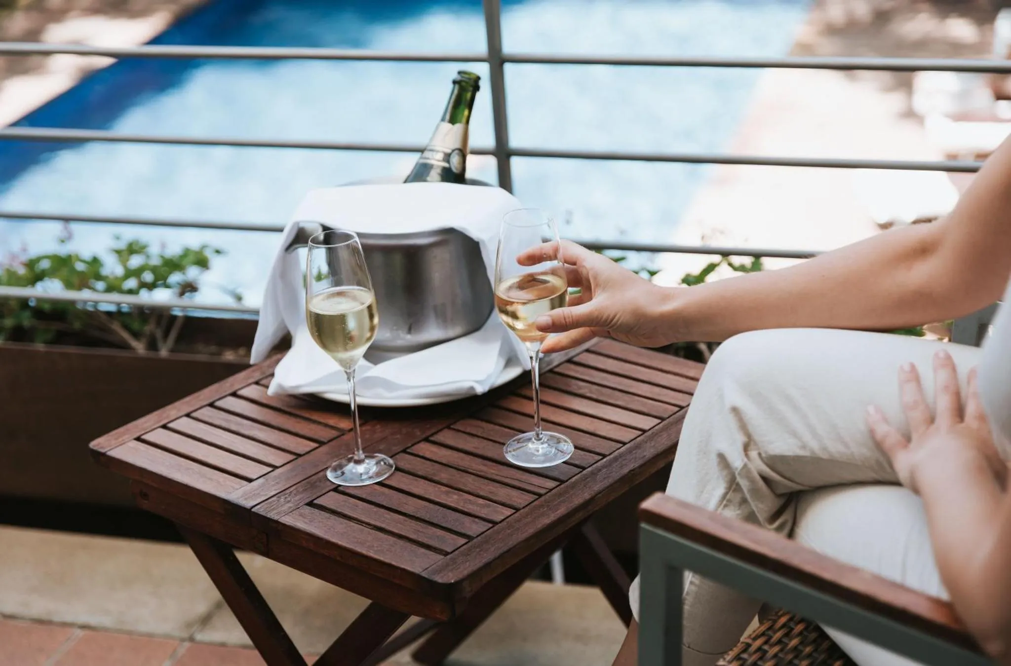 Une table en bois avec des verres de vin et une bouteille fraîche sur une terrasse ensoleillée.