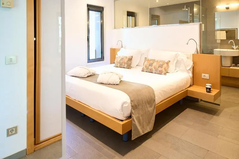 Une chambre lumineuse avec un grand lit et une salle de bain ouverte.