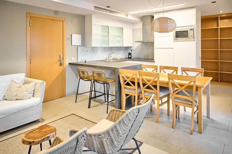 Une cuisine ouverte sur un espace repas avec des tabourets et une table en bois.