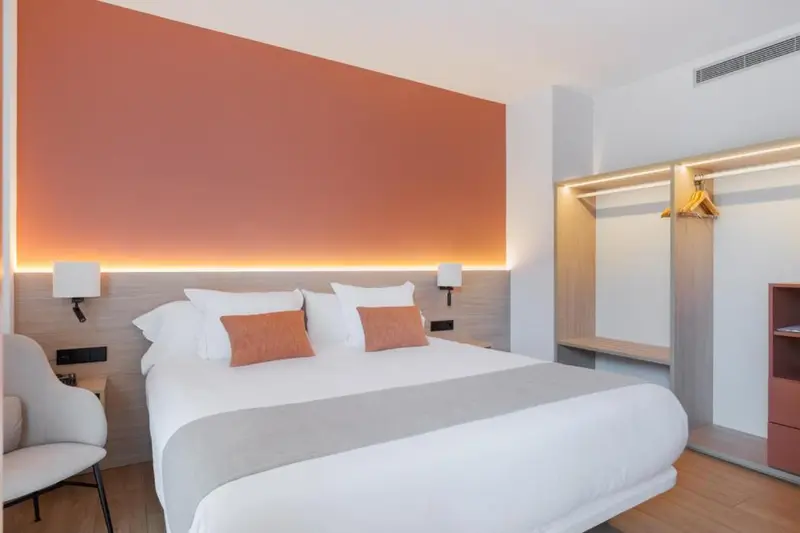 Une chambre moderne avec un grand lit et un éclairage chaleureux.