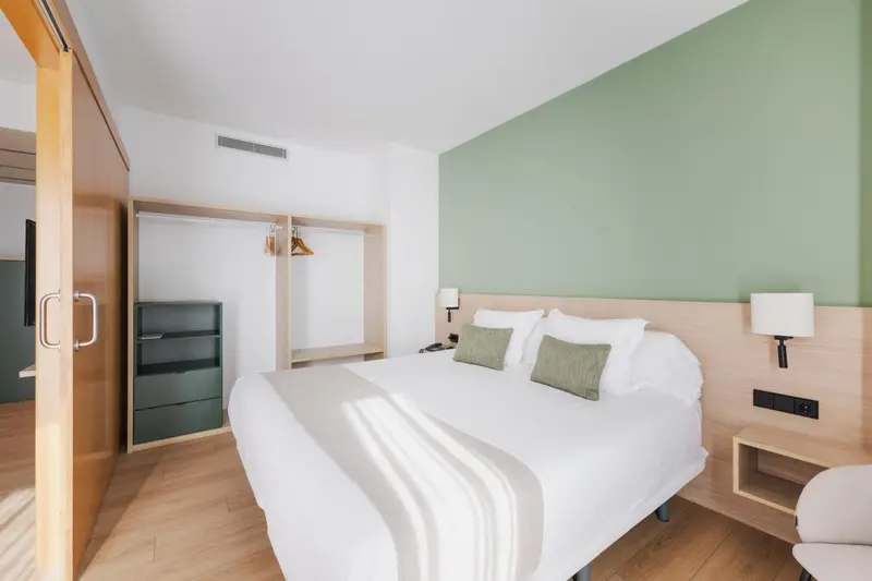Chambre lumineuse avec un grand lit et un espace de rangement.