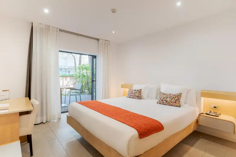 Une chambre lumineuse avec un grand lit et un accès à une terrasse.