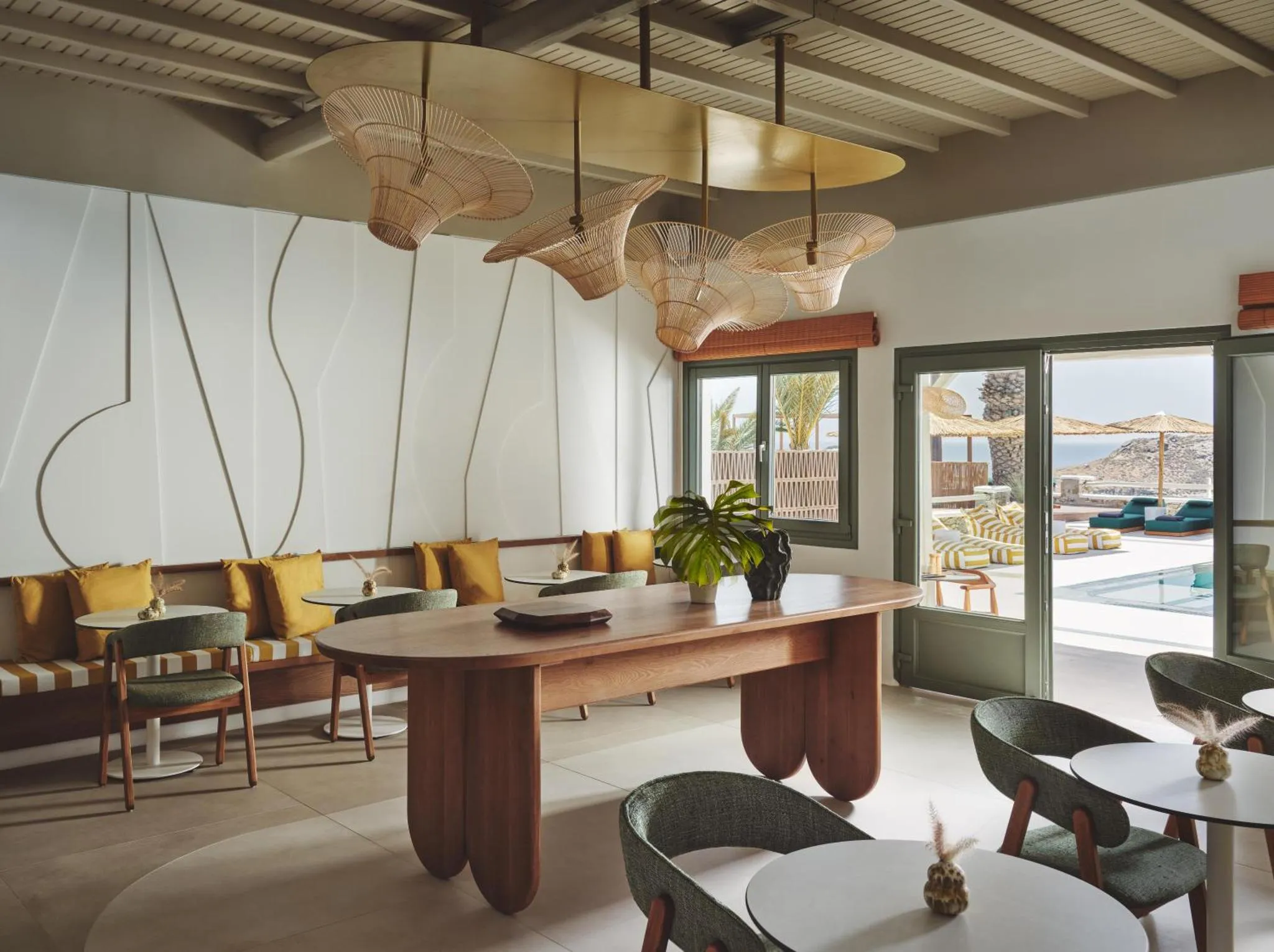 Une table en bois est entourée de chaises et de banquettes dans une salle lumineuse.