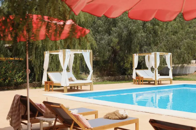 Transats et parasols ombragent une piscine en extérieur.