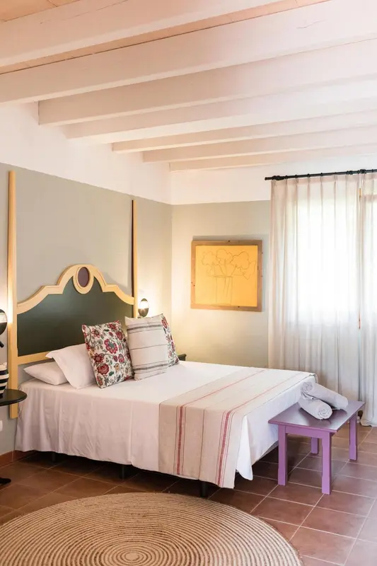 Une chambre lumineuse avec un grand lit recouvert d'une courtepointe.