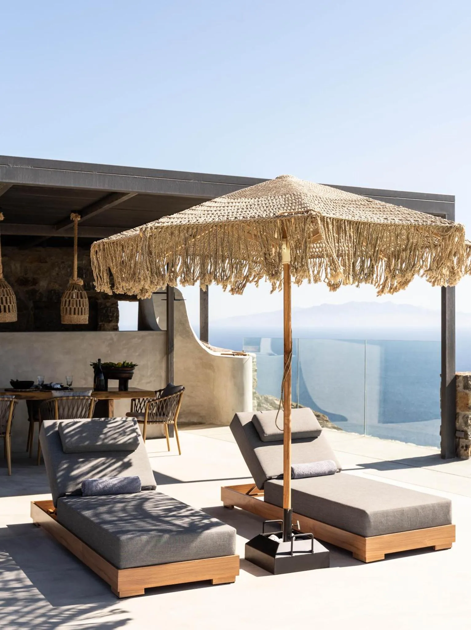 Terrasse ombragée avec transats et table à manger donnant sur la mer.