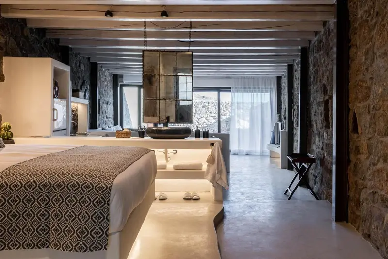 Une chambre lumineuse avec un grand lit et un espace baignoire ouvert.