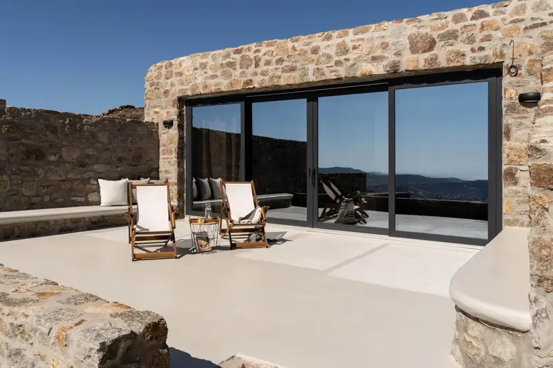 Terrasse aménagée avec des fauteuils en bois et une vue sur le paysage.