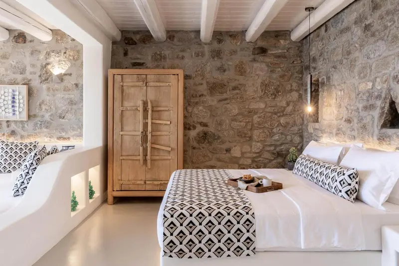 Une chambre lumineuse avec un lit recouvert d'une couverture à motifs géométriques.