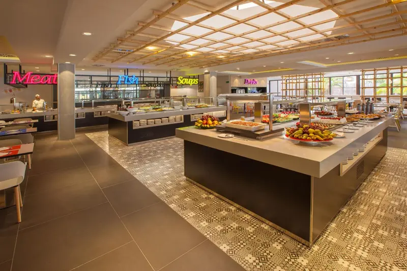 Un buffet propose une grande variété de plats et de salades dans une salle lumineuse et moderne.