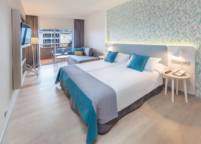 Une chambre lumineuse avec un grand lit et un coin salon.