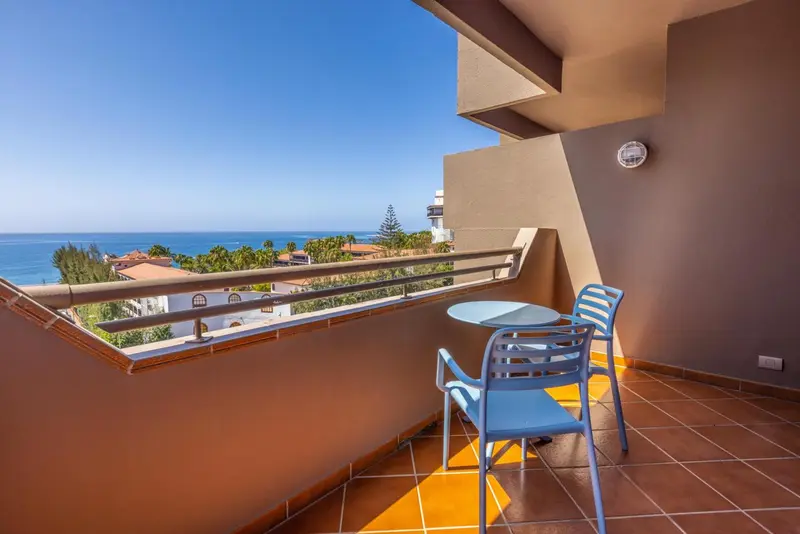 Balcon avec mobilier de jardin et vue sur la mer.