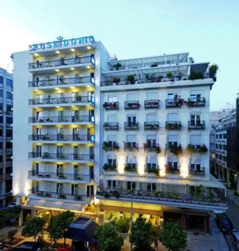 Bâtiment blanc à plusieurs étages avec des balcons fleuris et une façade lumineuse.