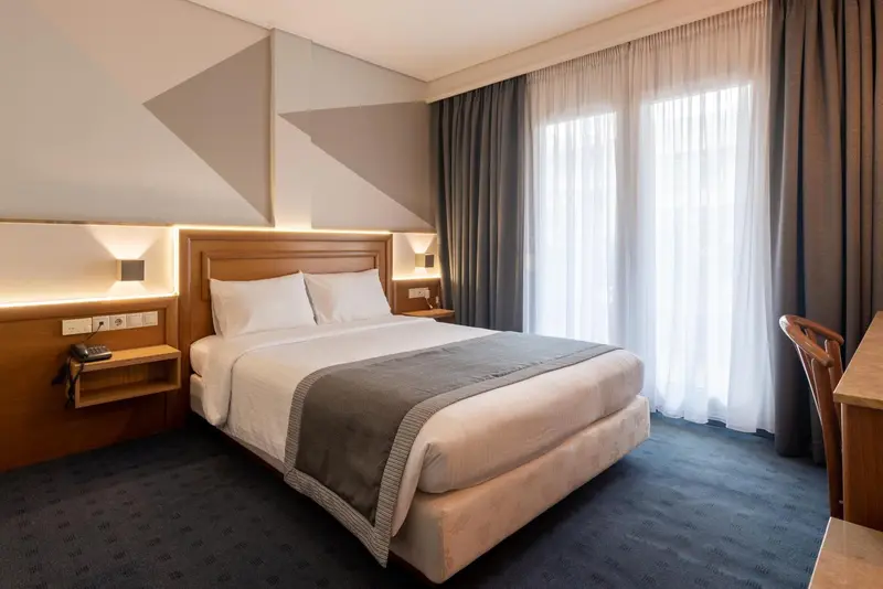Une chambre d'hôtel moderne avec un lit double et des rideaux clairs.